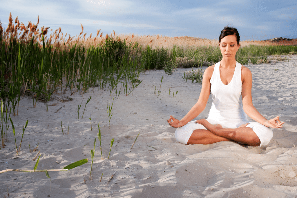 A woman is meditating on the beach.