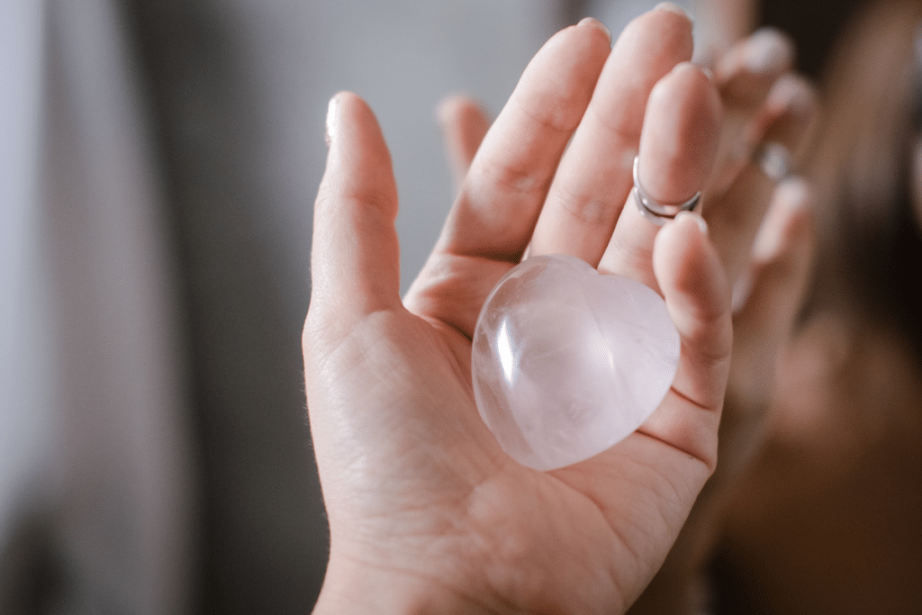 A woman's hand holding a piece of pink quartz.