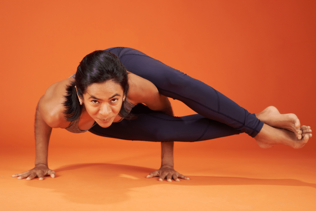 A woman doing a yoga pose on an orange background.