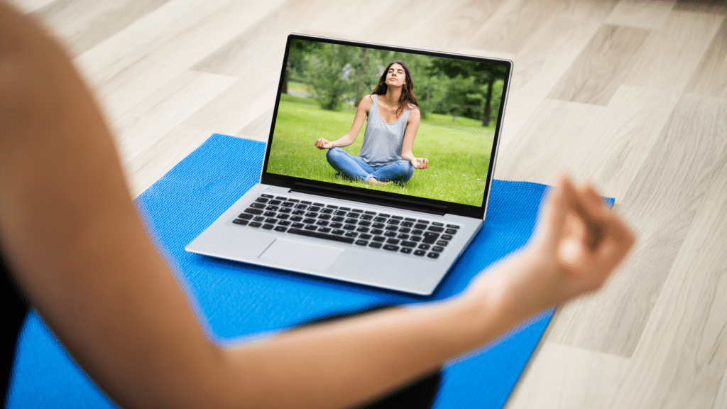 A woman doing yoga on a laptop.