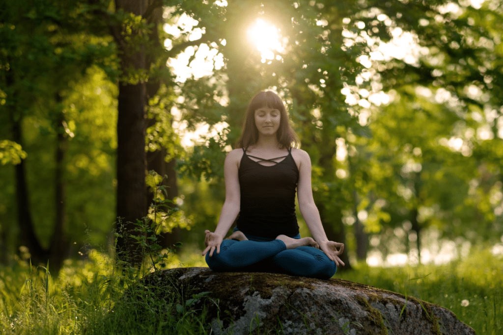 A woman is meditating in the woods.