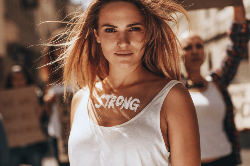 A woman wearing a shirt with the word strong written on it.