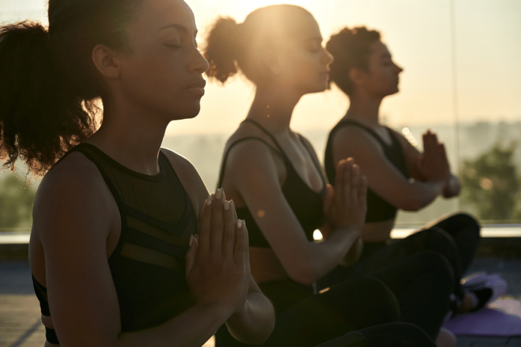 A group of women doing yoga in front of a window.