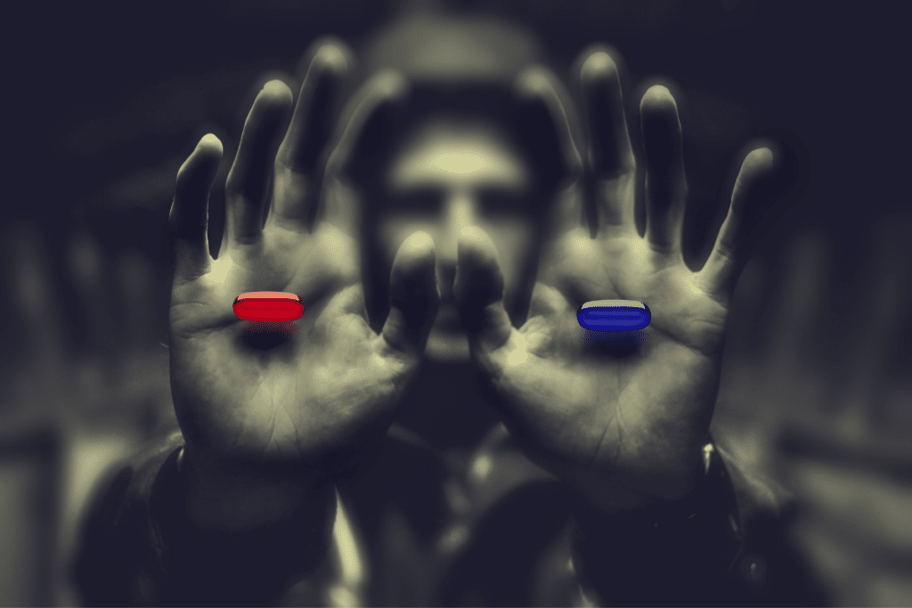 A man's hands are holding two blue and red pills.