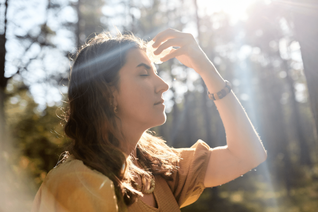 A woman looking at the sun in the forest.