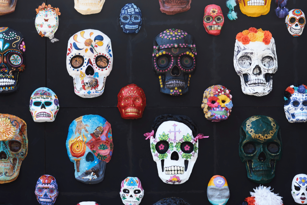 Many sugar skulls are displayed on a black wall.