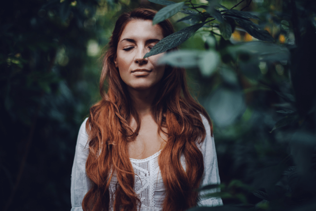 A woman with red hair in the forest.