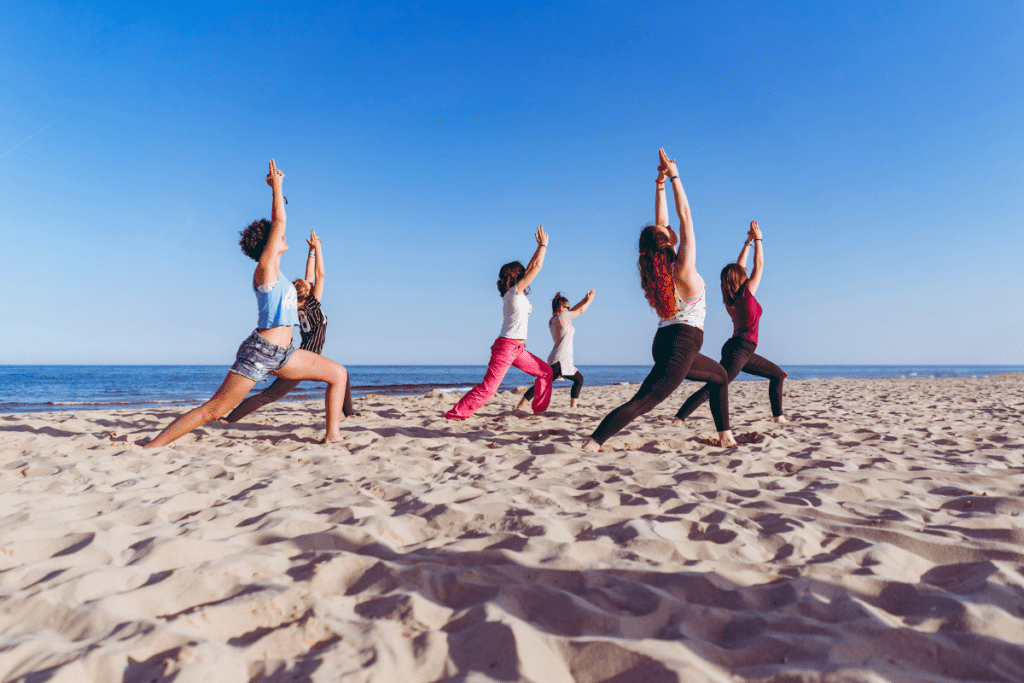 A group of women doing yoga on the beach.